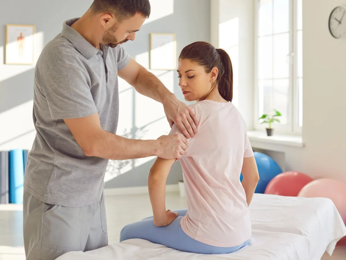 Physiotherapeutin behandelt einen Patienten in einer deutschen Praxis